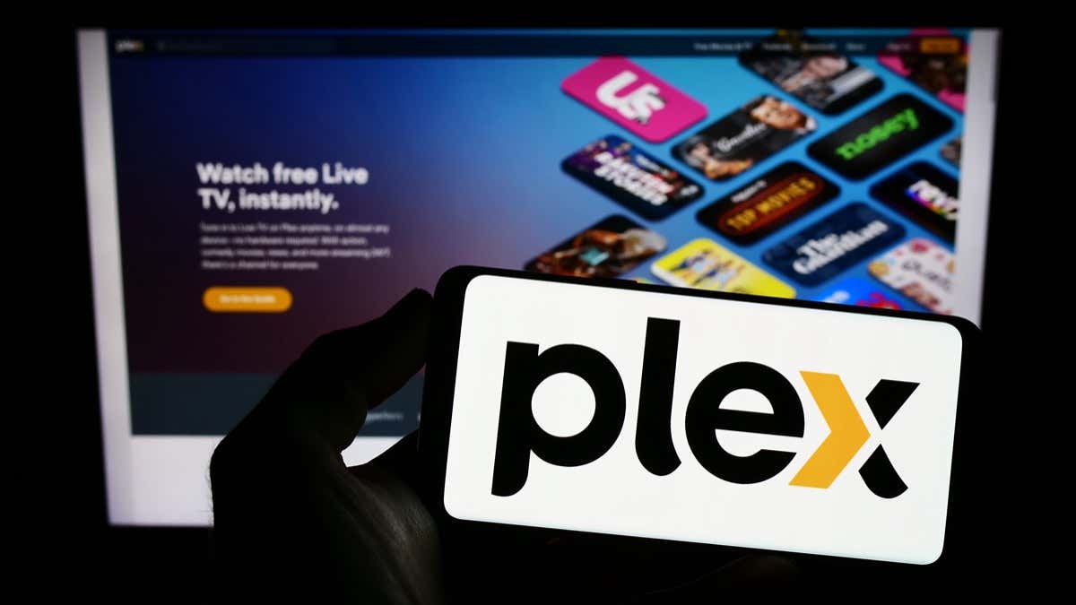 A hand holds a smartphone displaying the Plex logo
