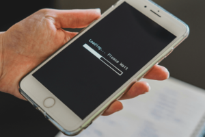 A hand holds a smartphone displaying a loading bar with the text "Loading