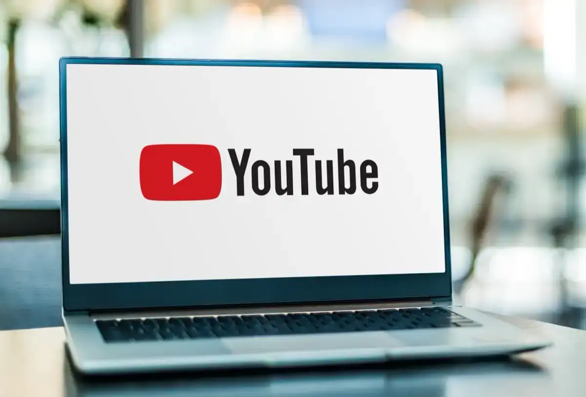 A laptop displays the YouTube logo—a red play button